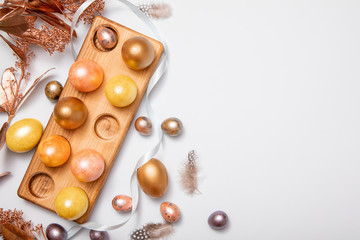 Easter eggs decorations with flower branches and bird feather on pastel blue table. Top view, flat lay