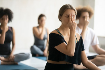 Woman doing Alternate Nostril Breathing exercise close up, practicing yoga