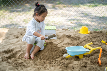 Cute little girl playing with sand at playground.