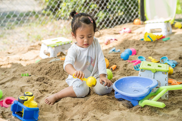 Cute little girl playing with sand at playground.