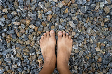 Feet standing on small grey stones.