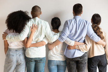 Back view of multiracial friends hug showing unity and support