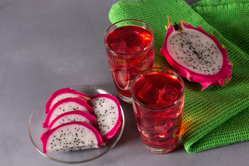 Glass of mango dragonfruit refresher drink on grey table with ice cubes. Copy space.