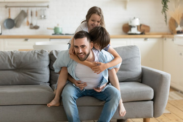 Father playing enjoy active games with little children at home