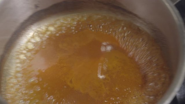 Orange boiling sauce in the metal pan. Top view