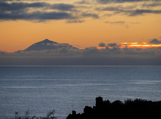 Beautiful orange sunrise over calm ocean and mountain pico del Teide at Tenerife seen from La...