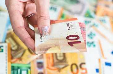 Hand giving money like bribe or tips isolated on banknotes background. EURO and USD currency...