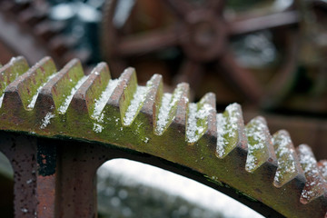 a close up of a rusty iron gear with snow on it