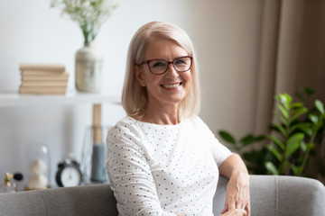 Headshot portrait of happy elderly woman relax at home