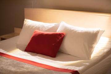 few pillows red and white on bed , rest day.