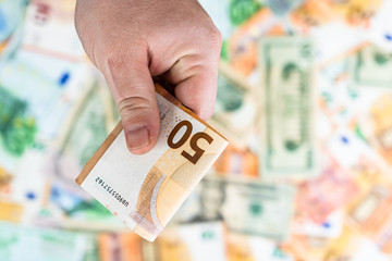 Hand giving money like bribe or tips isolated on banknotes background. EURO and USD currency...