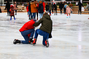 Winter ice rink. A group of People ride fun and fall on the ice. Active family sport during children's Christmas winter break. School sports clubs. Dnipro city, Dnepropetrovsk, Ukraine