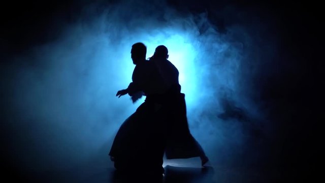 Silhouette two martial arts Aikido fighter on spotlight background.