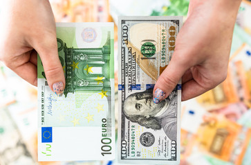 Hand holding money isolated on banknotes background. EURO and USD currency banknotes compared close...