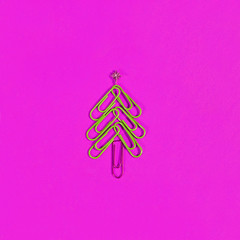 Christmas tree shape made from paperclips, with a gold star. christmas day and new year's concept in office. pink Background for stationery and Christmas discounts