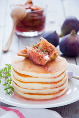 A stack of homemade pancakes with fig jam on a white plate
