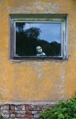 Gruselige Puppe am Fenster in einem alten Haus