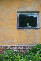 Gruselige Puppe am Fenster in einem alten Haus
