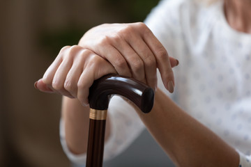 Close up of disabled senior woman hold walking cane