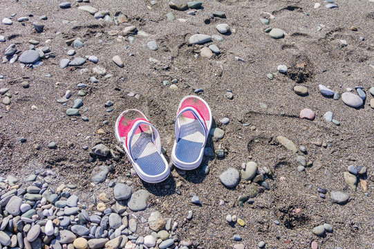 Children's flip flops on the beach. Copy space. Tourism and vacation concept