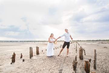 Young woman with her husband standing at the bottom of a dried salt lake against the background of the setting sun. abandoned salt production