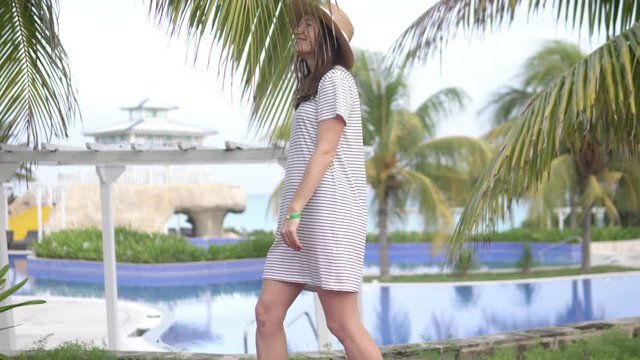 A beautiful woman in a hat walks around a hotel in Cuba