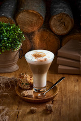 Cafe latte macchiato layered coffee in a glass cup.The cup is on a rustic Wooden Table