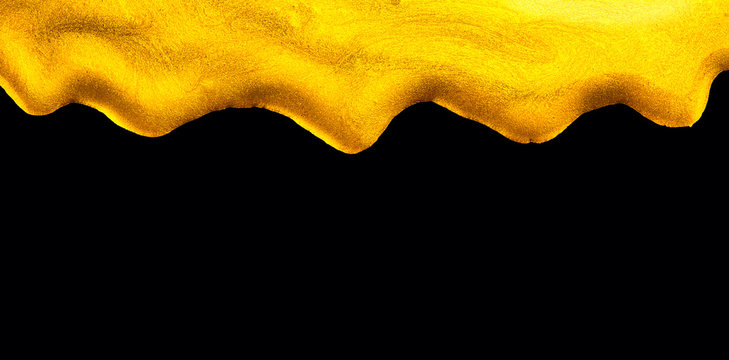 Golden dripping liquid paint texture, isolated on black background. Flowing abstract Gold metallic paint drops close-up. Leaking Lipgloss, blots of nail polish closeup. Border art design