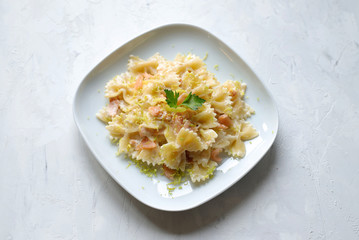 Farfalle con salmone affumicato, salsa di panna e limone sul piatto bianco