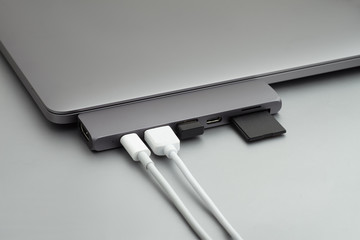 Space grey laptop with usb hub, white wires, usb reciver and sd card