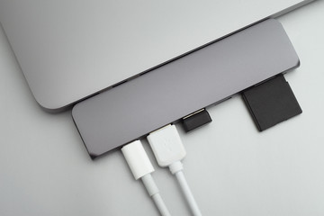 Space grey laptop with usb hub, white wires, usb reciver and sd card