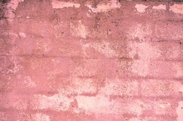 Fragment of old house wall close-up. Pink background. Peeling plaster on concrete surface. Cracks in paint. Copy space. Place for text. Selective focus image.