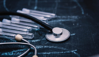 concept of medical diagnosis and therapy, stethoscope and test tubes on a dark background.
