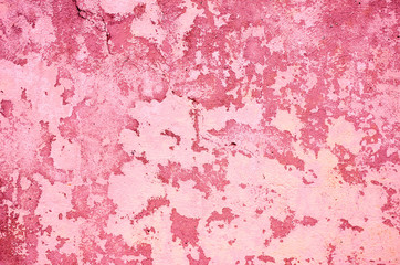 Fragment of old house wall close-up. Pink background. Peeling plaster on concrete surface. Cracks in paint. Copy space. Place for text. Selective focus image.