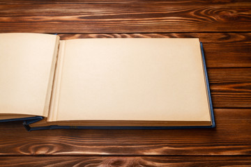 Old photo album with photos on a wooden table. Mockup free. Copy space.