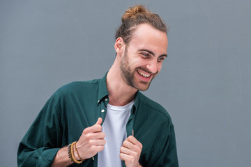 Close up horizontal portrait of young man with beard against gray background laughing and looking away