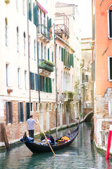 Men gondoliers drive gondolas with tourists in Venice in Italy.