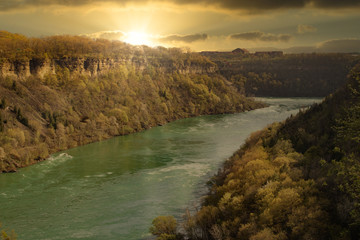 Obraz premium golden rays of sunshine over the river in the valley at sunset
