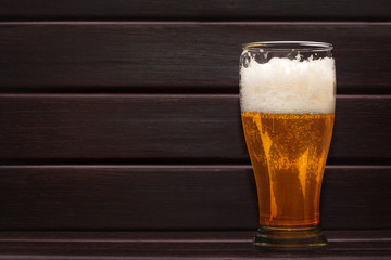 Glass of beer on dark wooden background