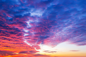 Sunset fire in the sky. Dark blue clouds with red reflections of the setting sun. Scenic sundown cloudscape for background. Dramatic cloudscape at sunset.