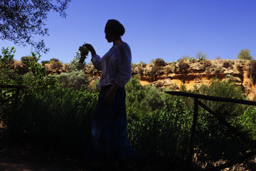 Woman in the shade, in a turban, with grape. The Valle dei Templi, Giardino della Kolymbetra, Agrigento, Sicily, Italy
