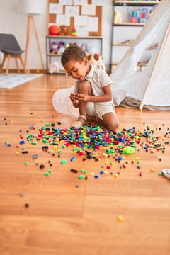Beautiful african american toddler playing with small building blocks at kindergarten