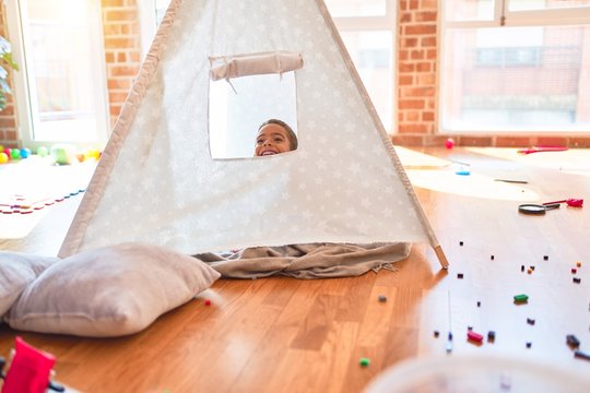 Beautiful african american toddler playing inside tipi smiling at kindergarten