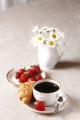 Breakfast. Croissant and strawberry. And black coffee, a bouquet of flowers. Fresh strawberries. 