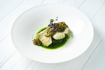 Close up on gourmet Grilled fillet of pike perch on a pillow of stewed spinach with green sauce. Healthy food. Restaurant food.