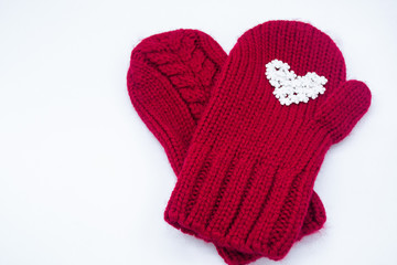 Two knitted red mittens lie on top of each other, one of them has white snowflakes in the shape of a heart on a white background, isolated. Concept of Christmas, winter, love and St. Valentine's day