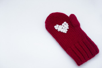 A knitted red mitten with white snowflakes in the shape of a heart on a white background, isolated. Сoncept of Christmas, winter, love, care and Valentine's day. Copy space