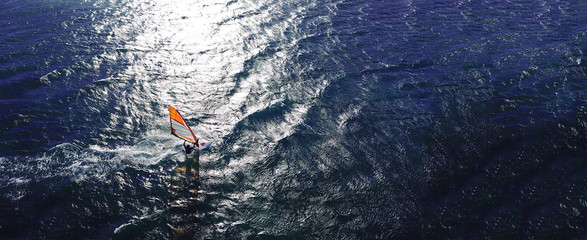 Aerial drone ultra wide photo of wind athlete surfer practising in deep blue open ocean sea