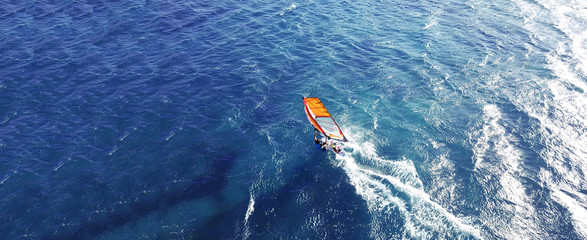 Aerial drone ultra wide photo of wind athlete surfer practising in deep blue open ocean sea