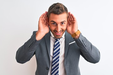 Young handsome business man wearing suit and tie over isolated background Trying to hear both hands on ear gesture, curious for gossip. Hearing problem, deaf